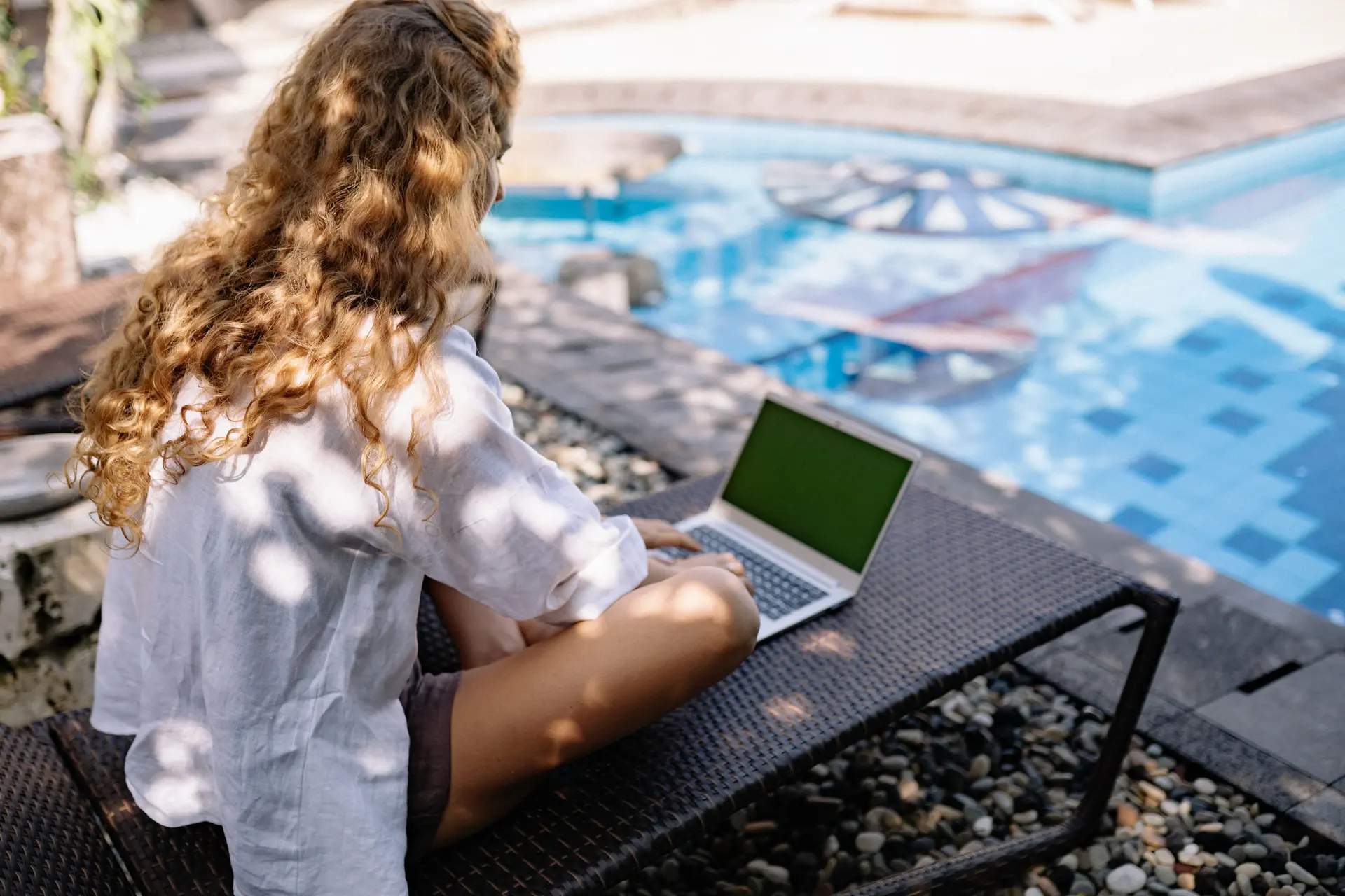 Pessoa trabalhando no notebook à beira da piscina, rotina de quem ganha em dólar trabalhando de qualquer lugar