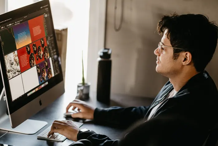 Designer trabalhando em frente a um computador com ferramenta de criação aberta na tela