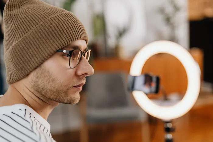 Criador de conteúdo gravando um vídeo com o celular em um anel de luz