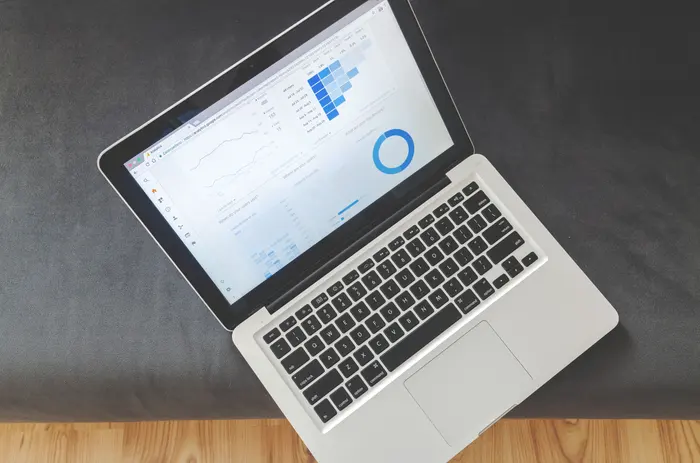 Notebook aberto sobre um sofá mostrando um painel de métricas de marketing digital