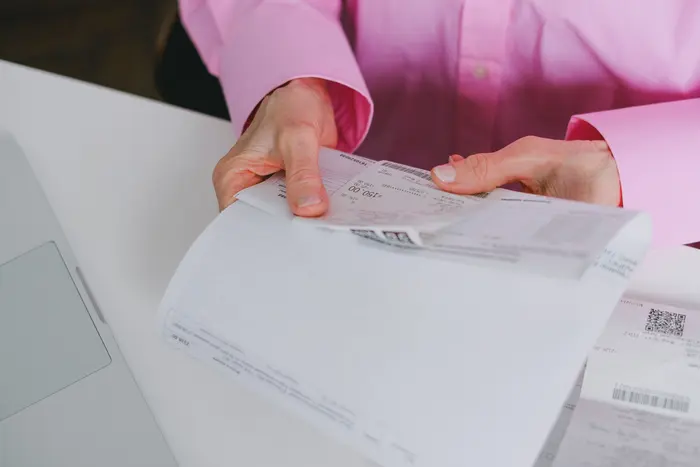 Pessoa conferindo um orçamento impresso em papel ao lado do notebook