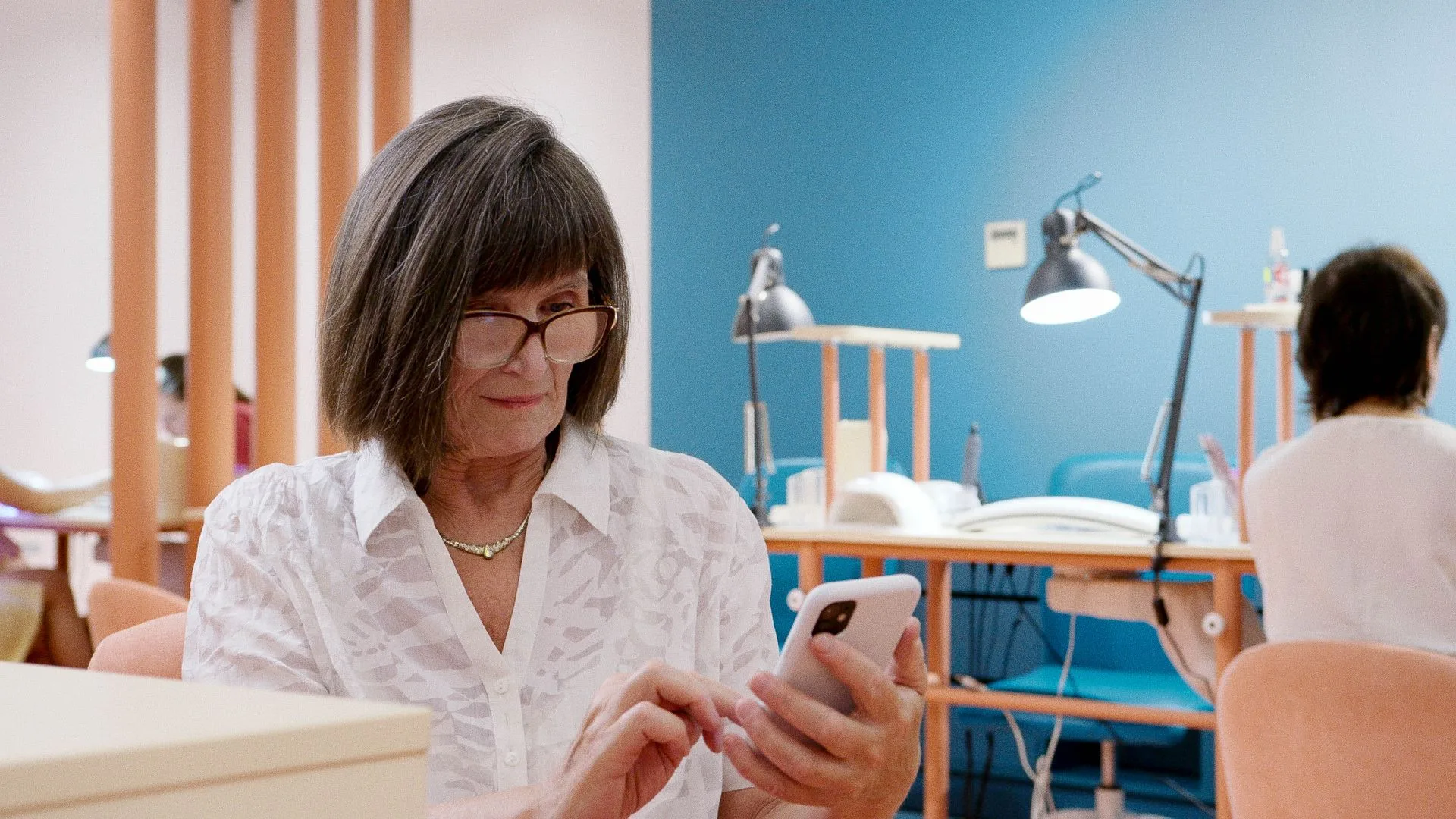 Dona de salão de beleza sorrindo enquanto mexe no celular