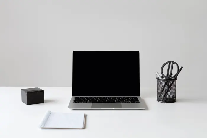 Notebook aberto numa mesa minimalista, tela em preto esperando o comando certo
