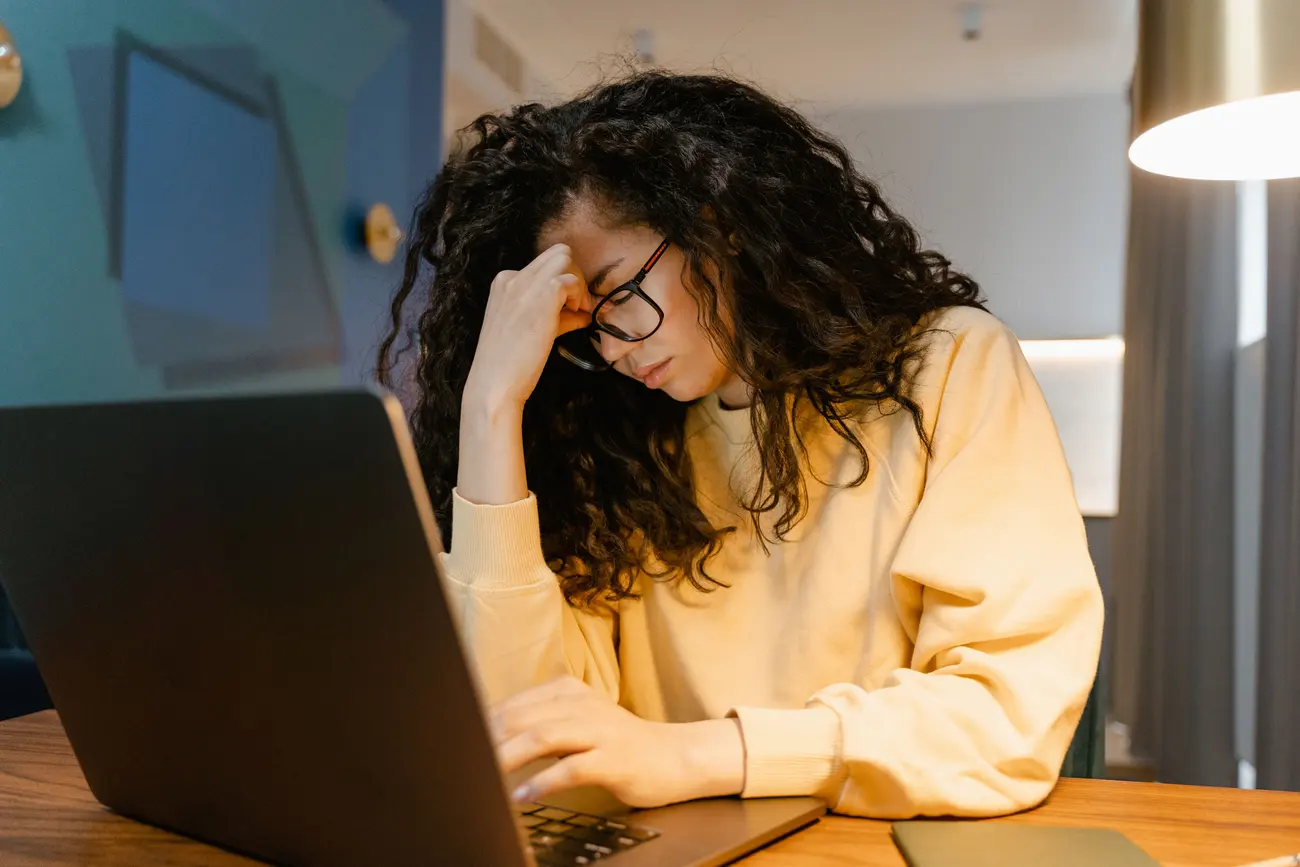 Pessoa cansada em frente ao notebook, mão na testa, depois de uma resposta que não ajudou