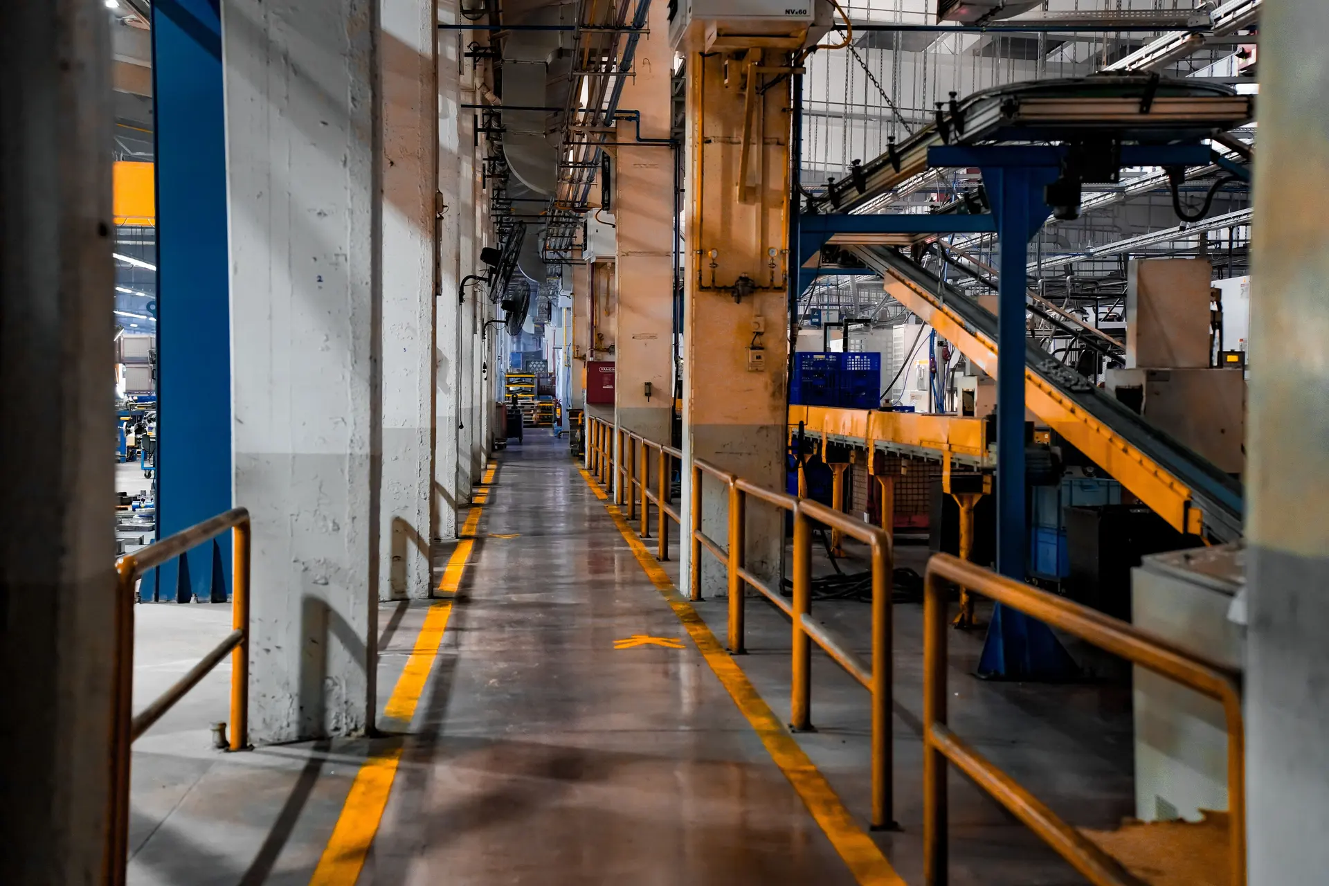 Corredor vazio de uma fábrica com estruturas metálicas e iluminação industrial