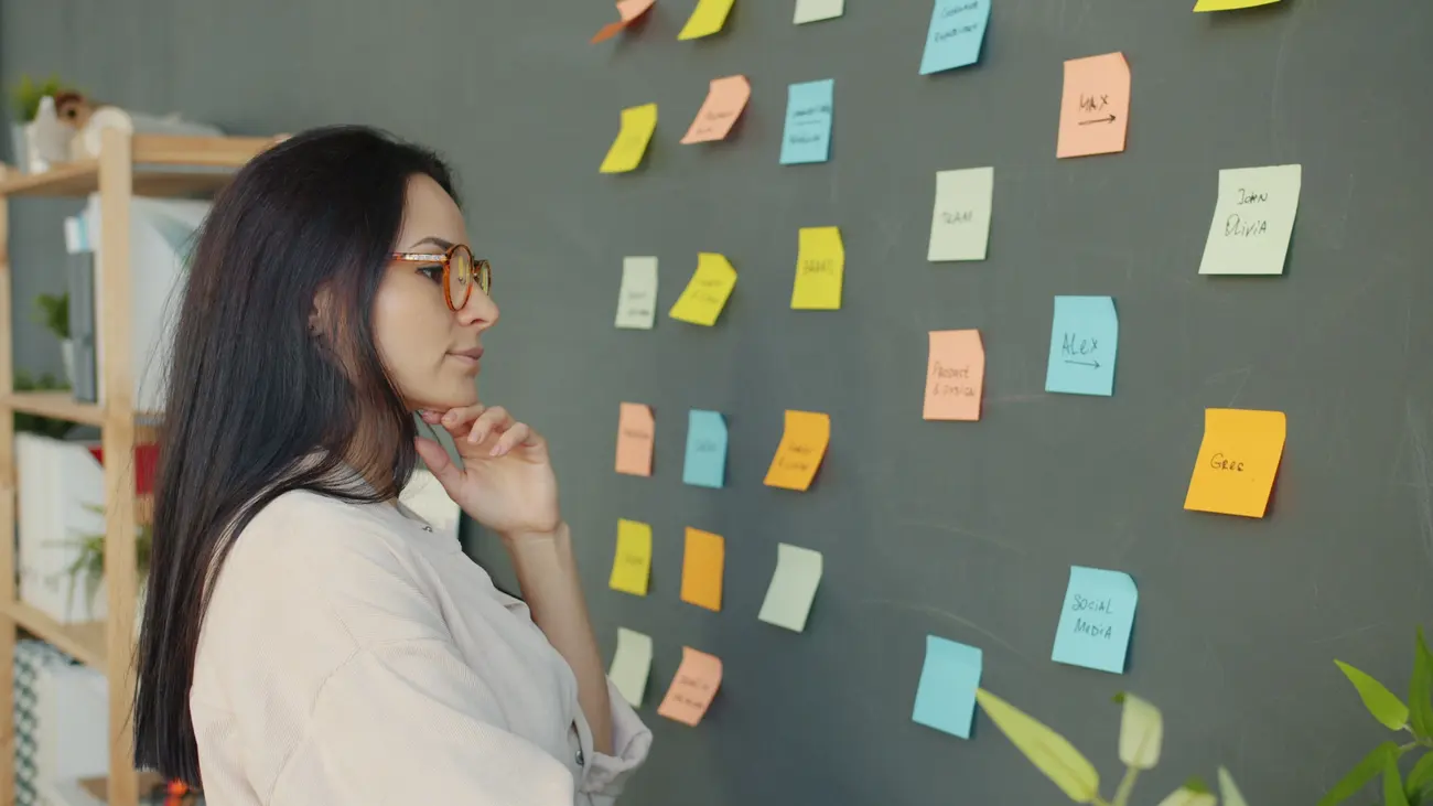 Mulher observando um mural de post-its coloridos durante uma sessão de brainstorm de conteúdo