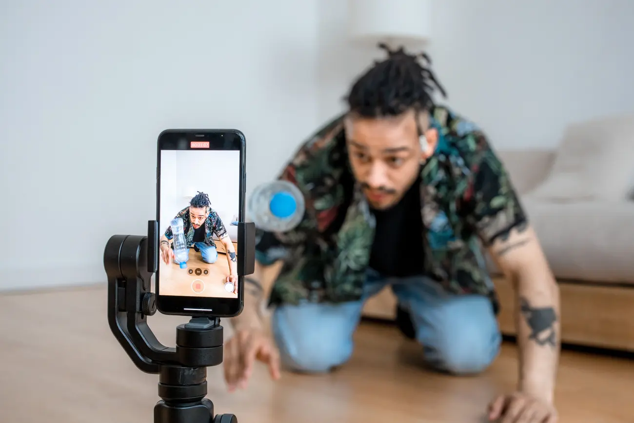 Pessoa gravando um vídeo com o celular preso em um estabilizador, mostrando o processo em close