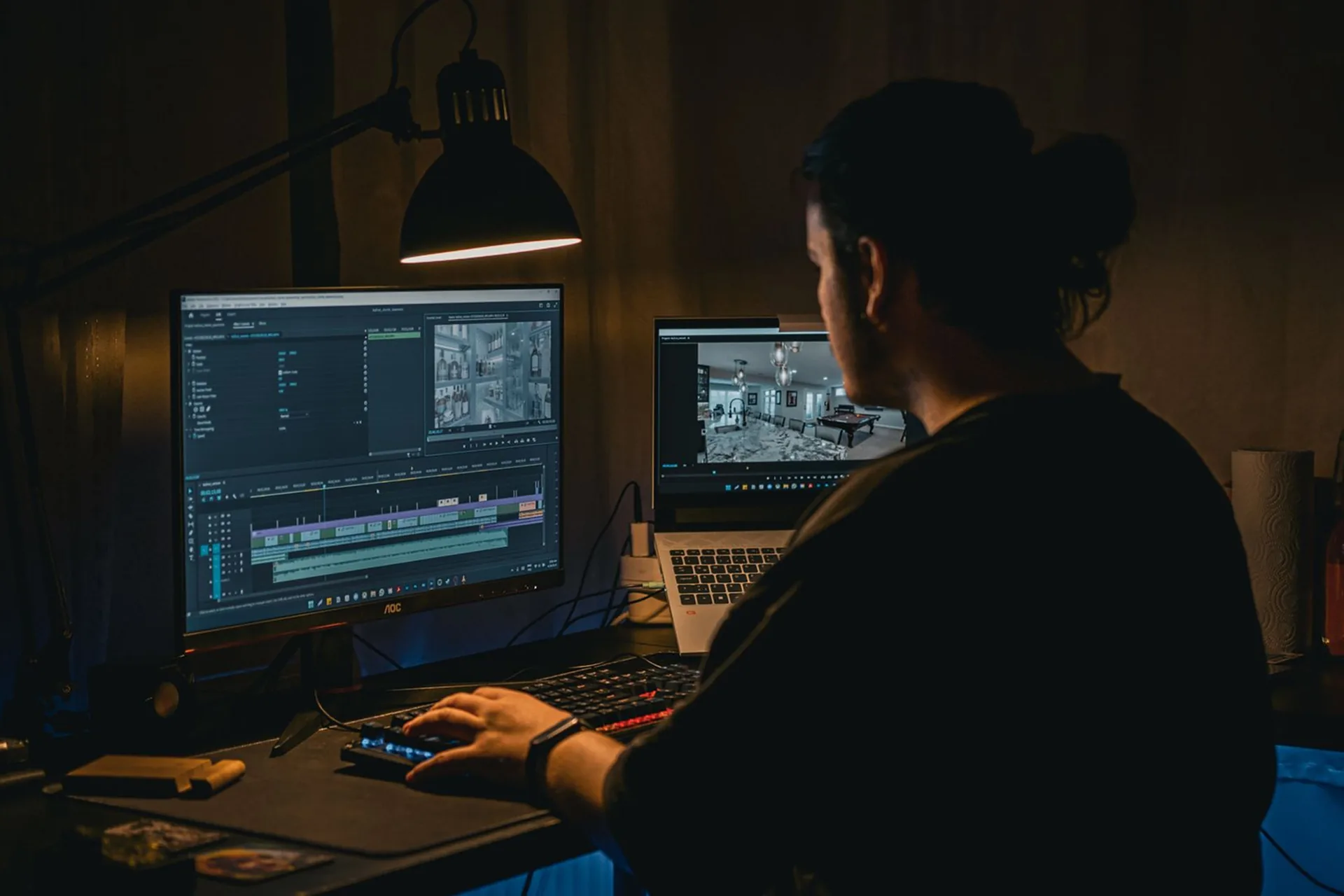 Pessoa editando vídeo à noite num computador com dois monitores e a linha do tempo da edição na tela