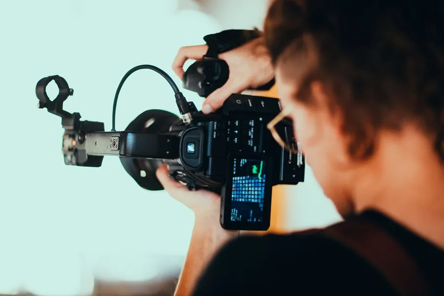 Videomaker filmando com câmera profissional em close